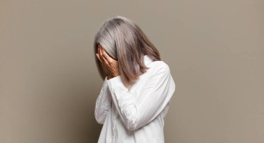 Son sınıf öğrencisi kadın, üzgün, hayal kırıklığına uğramış bir bakışla, ağlayarak, yan gözle gözlerini kapatıyor.