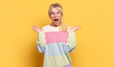 Sarışın kadın mutlu, heyecanlı, şaşırmış ya da şaşırmış hissediyor. İnanılmaz bir şeye gülümsüyor ve şaşırıyor.