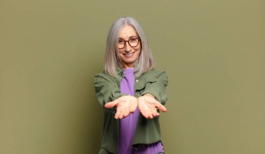 Son sınıf öğrencisi mutlu bir şekilde gülümseyen, kendine güvenen, olumlu bakan, bir nesne ya da konsept sunan ve gösteren bir kadın.