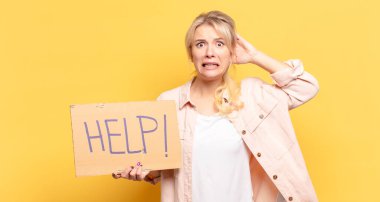 Sarışın kadın kendini stresli, endişeli, endişeli ya da korkmuş hissediyor. Elleri başının üstünde, hatayla panikliyor.