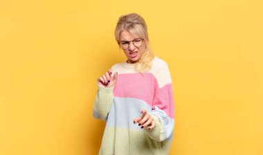 Sarışın kadın tiksinti ve mide bulantısı hissediyor. İğrenç, kokuşmuş ya da kokuşmuş bir şeyden kaçıyor.