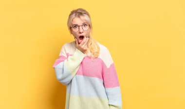 Sarışın, ağzı ve gözleri açık ve eli çenesinde olan bir kadın. Hoş olmayan bir şok geçiriyor. Ne diyor?