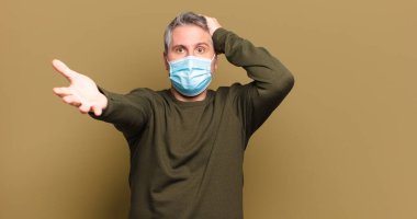 Koruyucu maskeli orta yaşlı bir adam.