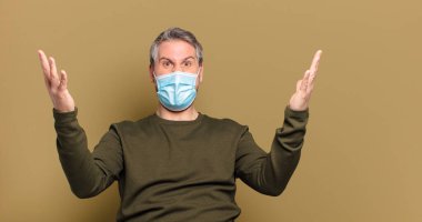 Koruyucu maskeli orta yaşlı bir adam.