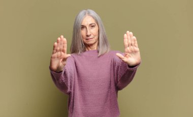 Yaşlı kadın ciddi görünüyor, mutsuz, kızgın ve hoşnutsuz giriş yasaklandı ya da her iki avuçta da dur diyor.