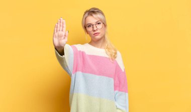 Sarışın kadın ciddi, sert, hoşnutsuz ve kızgın görünüyor.