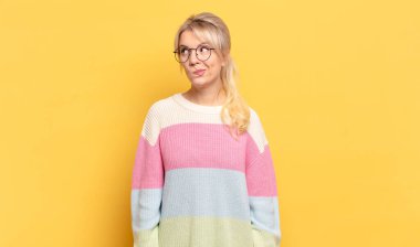 Sarışın kadın şaşkın ve şaşkın görünüyor, merak ediyor veya bir sorunu çözmeye çalışıyor veya düşünüyor.