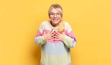 Sarışın kadın mutlu görünüyor, şaşırmış, gururlu ve heyecanlı, kendini gösteriyor.