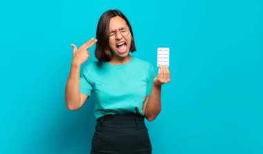 Genç İspanyol kadın mutsuz ve stresli görünüyor, intihar jesti elle silah işareti yapıyor, kafasını işaret ediyor.