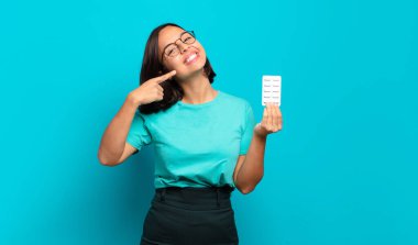 Genç İspanyol kadın kendine güvenerek gülümsüyor. Geniş gülümseme, pozitif, rahat, tatmin olmuş tavır.