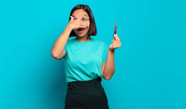 Genç İspanyol kadın şok olmuş, korkmuş ya da korkmuş görünüyor. Yüzü elle kaplanmış ve parmaklarının arasından gizlice bakıyor.