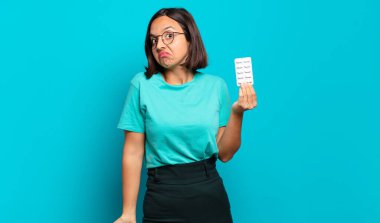 Genç İspanyol kadın omuz silkiyor, kafası karışık ve emin değil, kolları bağlı ve şaşkın görünüyor.