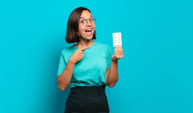 Genç İspanyol kadın heyecanlı ve şaşırmış görünüyor. Yan tarafı işaret ediyor ve uzayı kopyalıyor.