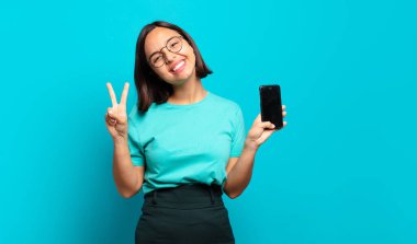 Genç İspanyol kadın gülümsüyor ve arkadaş canlısı görünüyor. İki ya da iki numarayı gösteriyor. Elleri önde, geri sayıyor.