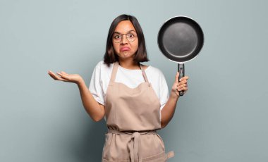 Genç İspanyol kadın şaşkın ve kafası karışık, şüpheci, farklı seçenekleri tartıyor veya komik bir ifadeyle seçiyor.