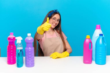 Genç, güzel ev bekçisi gururlu, tasasız, kendinden emin ve mutlu, başparmağıyla olumlu gülümsüyor.