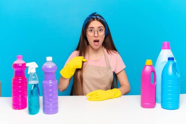 Genç, güzel bir ev bekçisi ağzı açık, şaşkın ve şaşkın bir şekilde kendini işaret ediyor.