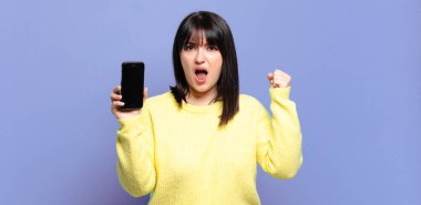 Artı boyut olarak güzel bir kadın sinirli bir ifadeyle agresif bir şekilde bağırıyor ya da yumruklarıyla başarıyı kutluyor.