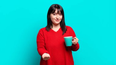 Artı boyut olarak güzel bir kadın mutlu bir şekilde gülümsüyor arkadaş canlısı, kendinden emin, olumlu bakışlı, bir nesne ya da konsept sunuyor ve gösteriyor.