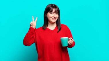 Artı güzel bir kadın gülümsüyor ve arkadaş canlısı görünüyor, iki ya da iki numarayı gösteriyor, elleri önde, geriye doğru sayıyor.