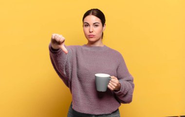 Genç, güzel bir kadın kızgın, sinirli, hayal kırıklığına uğramış ya da hoşnutsuz, ciddi bir bakışla başparmağını kaldırıyor.