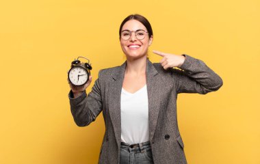 Genç, güzel bir kadın, kendine güvenerek gülümsüyor. Kendi gülüşünü gösteriyor. Olumlu, rahat, tatmin olmuş bir tavır.