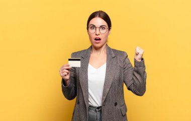 Genç ve güzel bir kadın öfkeli bir ifadeyle ya da yumruklarıyla başarıyı kutlarken agresif bir şekilde bağırıyor.