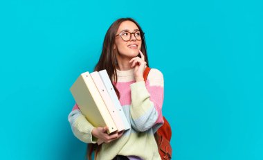 Genç ve güzel bir kadın mutlu bir şekilde gülümsüyor ve hayal kuruyor ya da şüphe ediyor.