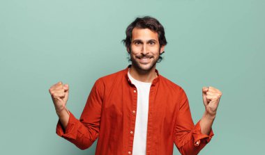 Genç, yakışıklı Hintli adam mutlu, şaşırmış ve gururlu hissediyor, bağırıyor ve başarıyı büyük bir gülümsemeyle kutluyor.