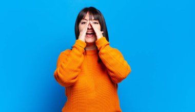 Ayrıca boyunda güzel bir kadın mutlu, heyecanlı ve pozitif hissediyor. Elleri ağızda, bağırıyor.