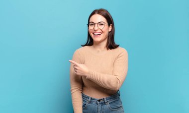 Genç, hoş, sıradan bir kadın heyecanlı ve şaşırmış görünüyor. Yana ve yukarıya bakıp boşluğu kopyalıyor.