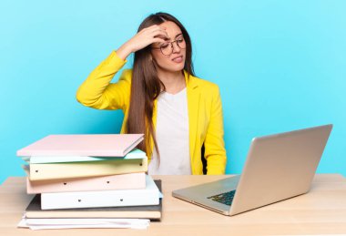 Genç ve güzel iş kadını stresli görünüyor, yorgun ve hayal kırıklığına uğramış, alnından ter damlıyor, umutsuz ve bitkin hissediyor.