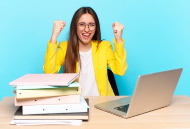 Genç ve güzel iş kadını mutlu, şaşırmış ve gururlu hissediyor, bağırıyor ve başarıyı büyük bir gülümsemeyle kutluyor.