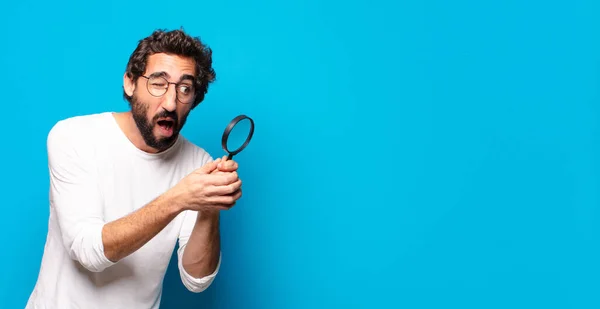 young crazy bearded man looking and trying to find with a magnifying glass