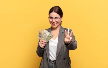 Genç, güzel bir kadın gülümsüyor ve arkadaş canlısı görünüyor. Üç ya da üç numarayı gösteriyor. Elleri önde, geriye doğru sayıyor.