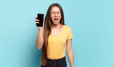 Genç ve güzel bir kadın agresif bir şekilde bağırıyor, kızgın, sinirli, öfkeli ya da sinirli görünüyor.