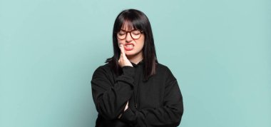 Artı, yanak tutan ve ağrılı diş ağrısı çeken, hasta, sefil ve mutsuz hisseden, dişçi arayan güzel bir kadın.