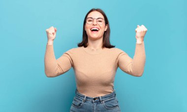 Genç, hoş, sıradan bir kadın mutlu, şaşırmış ve gururlu, bağırıyor ve başarıyı büyük bir gülümsemeyle kutluyor.