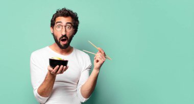 Erişteli ramen kasesi olan sakallı genç bir adam.