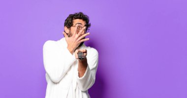 Uzaktan kumandalı bornoz giyen genç çılgın sakallı adam.