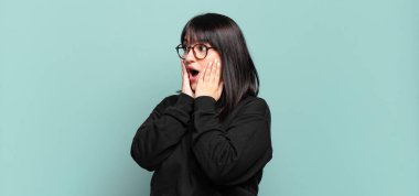 Ayrıca boyunda güzel bir kadın mutlu, heyecanlı ve şaşırmış hissediyor, iki eli yüzü üzerinde yana bakıyor.