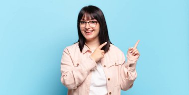 Artı boyut olarak güzel bir kadın mutlu bir şekilde gülümsüyor ve her iki elinle de fotokopi alanında nesne gösteriyor.