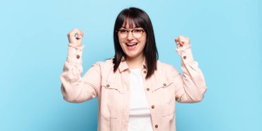 Artı boyunda güzel bir kadın muzaffer bir şekilde bağırıyor, heyecanlı, mutlu ve şaşırmış görünüyor, kutlama yapıyor.