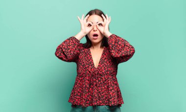 Genç, hoş, sıradan bir kadın şaşkın, şaşkın ve şaşırmış, elinde şaşkın, inançsız bir bakışla gözlük tutuyor.