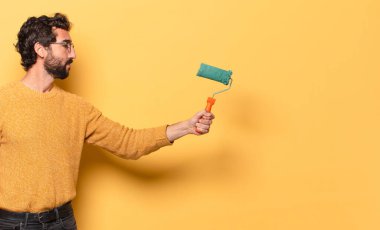 Boyalı silindirli ve duvar rengini değiştiren sakallı genç bir adam.