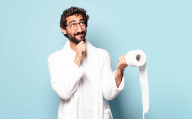 Bornoz ve tuvalet kâğıdı giyen çılgın sakallı genç adam.