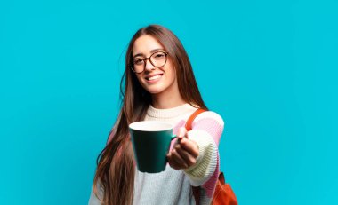 Elinde kahve fincanı olan genç ve güzel bir bayan öğrenci.