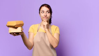 Önlüklü güzel bir kadın. Hamburger teslimatı konseptini kaldır