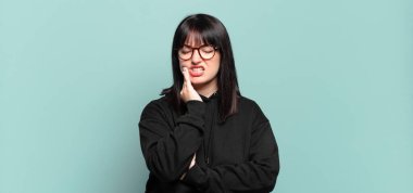 Artı, yanak tutan ve ağrılı diş ağrısı çeken, hasta, sefil ve mutsuz hisseden, dişçi arayan güzel bir kadın.