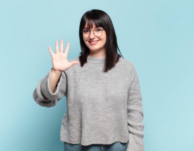 Artı, gülümseyen ve arkadaş canlısı görünen güzel bir kadın. 5 ya da 5 numarayı gösteriyor. Eli önde, geriye doğru sayıyor.